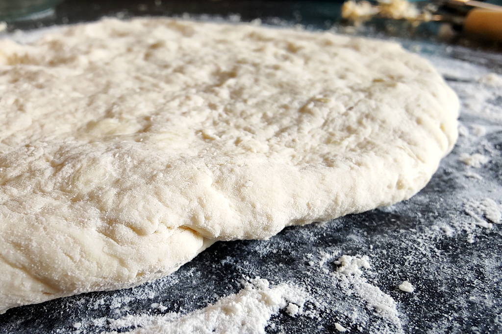Buttermilk biscuit dough flattened to 1/2 inch thickness, side view close up to show the thickness.
