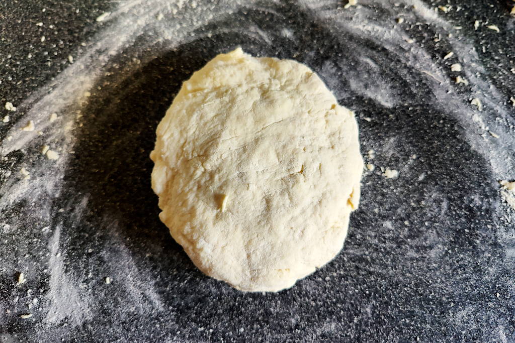 Buttermilk biscuit dough ball on a floured counter.