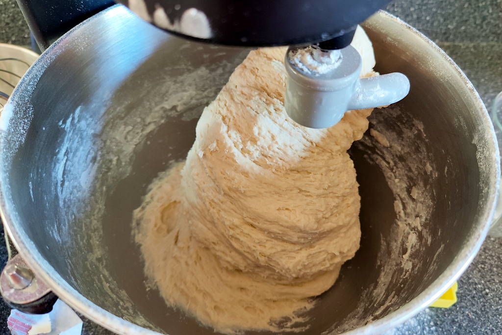 Sandwich bread dough being kneaded in a stand mixer.