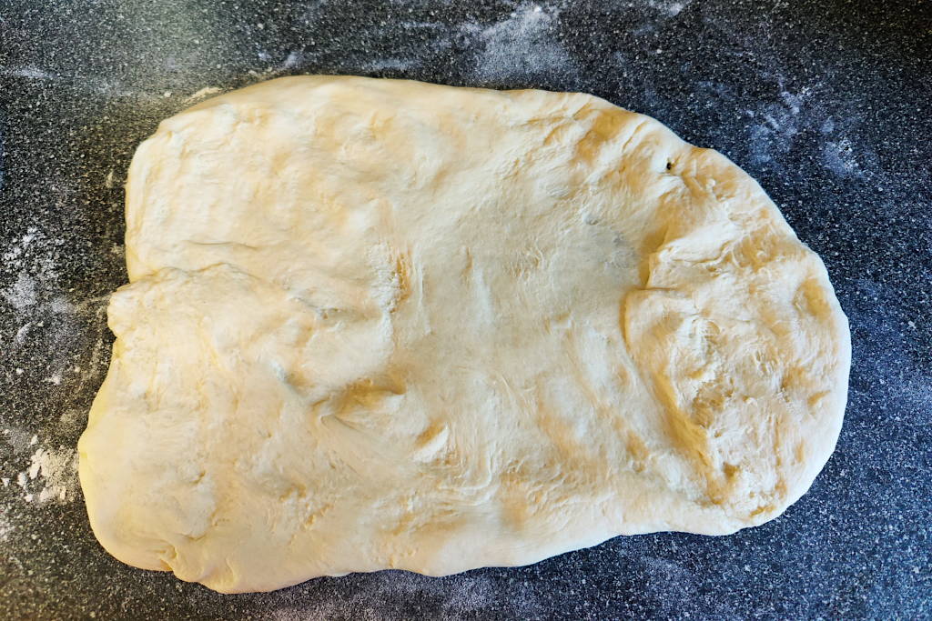 Sandwich bread dough shaped into a rectangle to roll into a log.